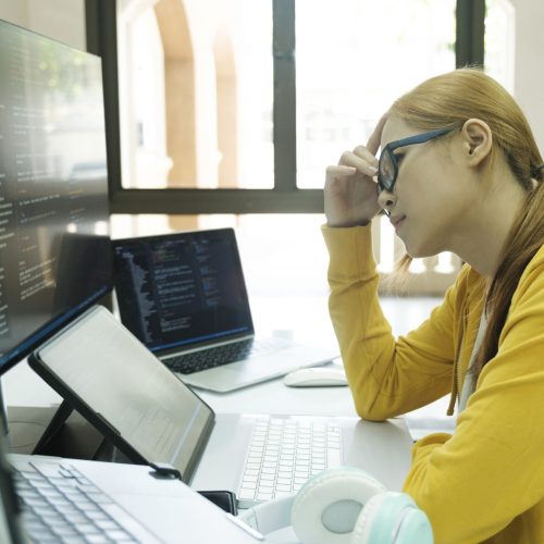 Young woman covering her face with the stress of work coding and Young woman covering her face with the stress of work coding and programming software. frustrated on her work and out of control.